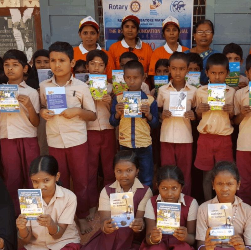 Schoolchildren holding books distributed by Rotary Coimbatore Manchester