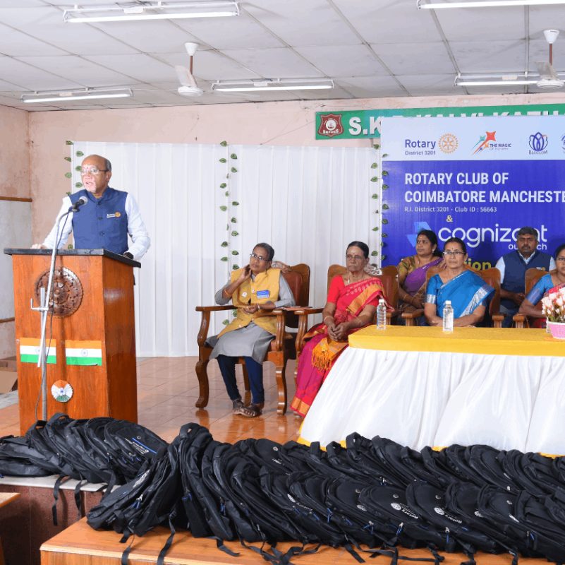A Rotary Coimbatore Manchester member speaking at a school bag distribution